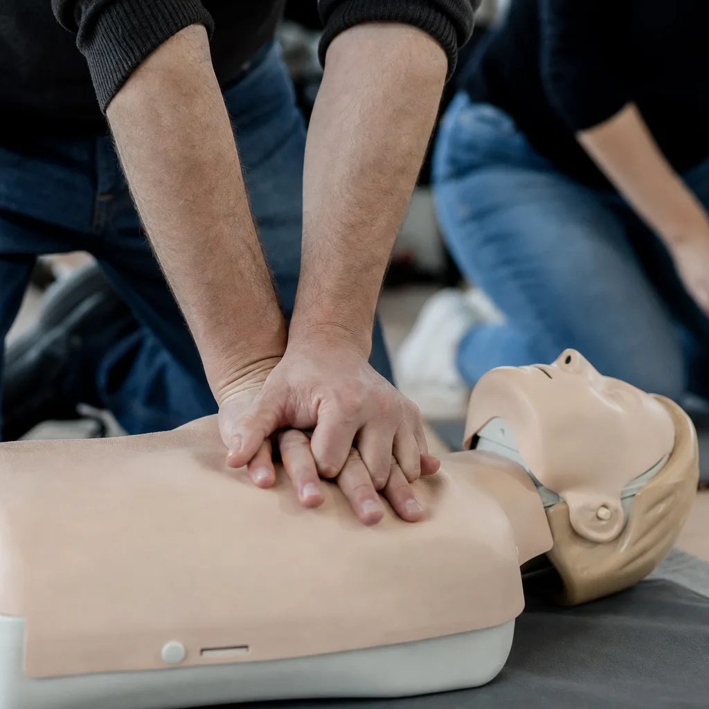 Mains d’un secouriste réalisant un massage cardiaque sur un mannequin de formation, sans visage visible.